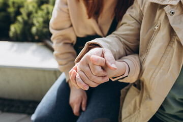 Two people holding hand together over blurred background. Giving a helping hand. Closeup of an elderly person's hand holding a young woman's. Symbol of compassion and solidarity