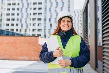 Happy Architect with paper folder with documents at a construction site. Successful woman...
