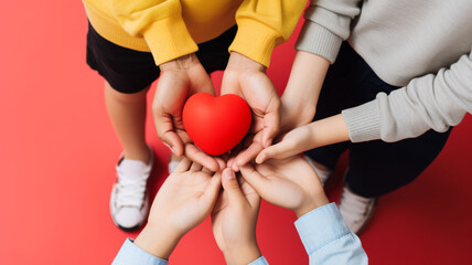 The hands of family members holding a red heart.