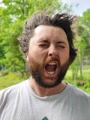 A man's face getting hit by wind, his eyes closed and mouth open