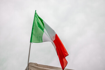 Italian national flag waving in the wind with blue sky used as background