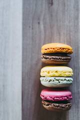 Assortiment de macarons colorés au chocolat framboise orange vanille citron alignés - Arrière plan coloré patisserie française	