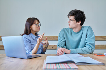 Young teenage male studying languages with teacher in classroom