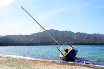 Blue boat stranded and abandoned on the beach of Saint Florent, a famous seaside resort in Corsica, nicknamed the Island of Beauty