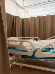 The adjustable hospital bed with a patient lying in the white blanket.