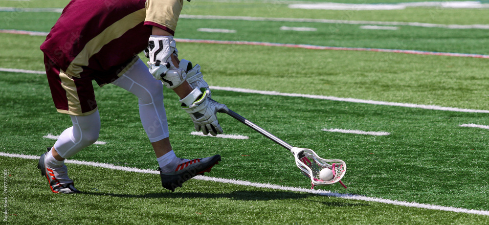 Wall mural Lacrosse player running and scooping up the ball during a game