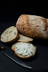 a slice of bread smeared with cottage cheese on a black background. Delicious and light breakfast
