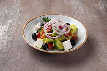 Greek salad in a plate on a brown background