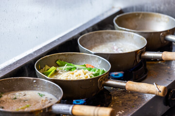 Cooking noodles in the open kitchen in restaurant