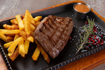 Steak and potatoes in a plate on a brown background.