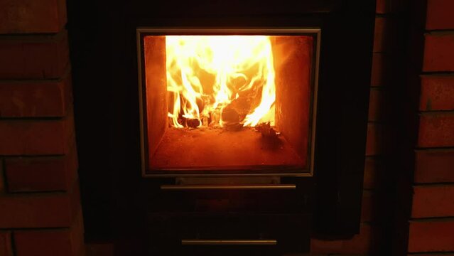 Close up stationary video of orange hot fire flame in fireplace. Wood plunks burning for the best heating. Central heating problem. Comfortable living and cozy atmosphere at country house