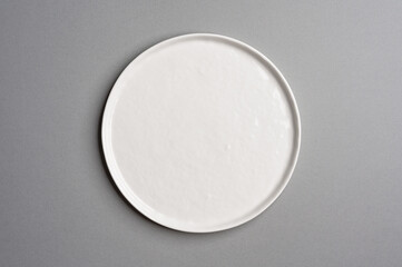 White flat empty plate on a light gray background. Top view.