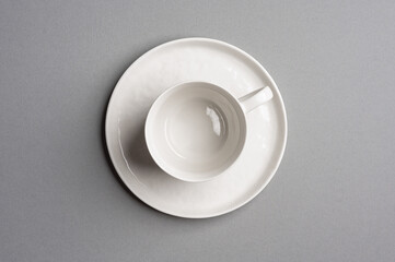 White empty cup with a saucer on a light gray background. Top view.