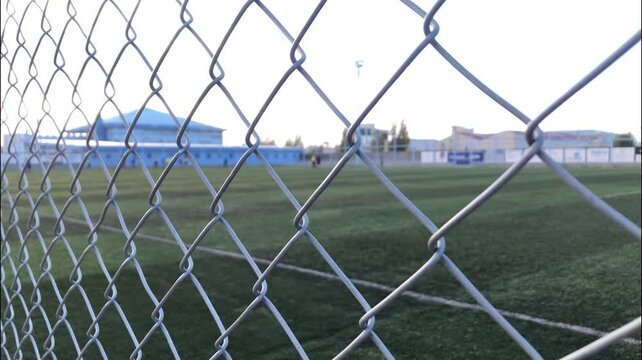 playing field through the Olympic mesh that surrounds it. Boys training soccer