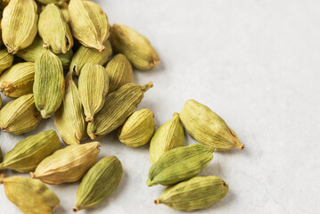 Cardamom pods with seeds on light textured background. Natural aromatic oriental spice with copy space