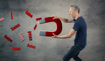 Happy man with a big magnet attracting sales