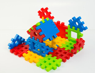 Plastic children's constructor on a white background. Figures from multi-colored details of the designer.