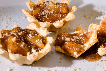 100mm Macro of 2 Apple Tartlets, small tarts, small pie, crumbs, shortbread crust and broken in pieces placed right.
