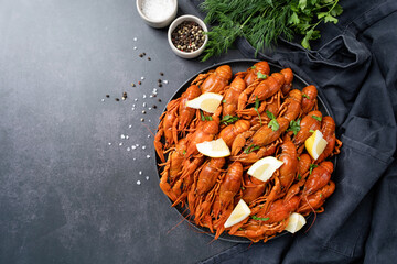 top view of cooked crawfish platter with lemons and spices on cement background