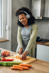 A cheerful Multiracial woman is singing while cooking at home.