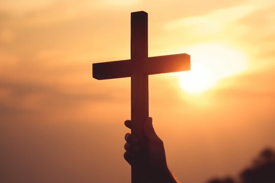 The silhouette of hands holding a wooden cross against a sunrise background creates a striking symbol of faith and the crucifixion.
