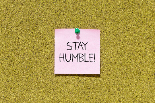 Stay humble text on pink post-it paper pinned on bulletin cork board. This message can be used in business concept about stay humble.