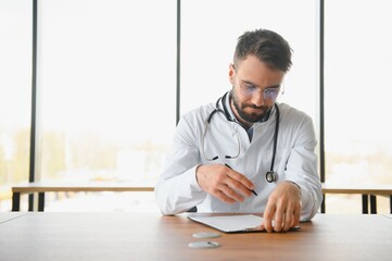 Young doctor sitting in his office behind a desk