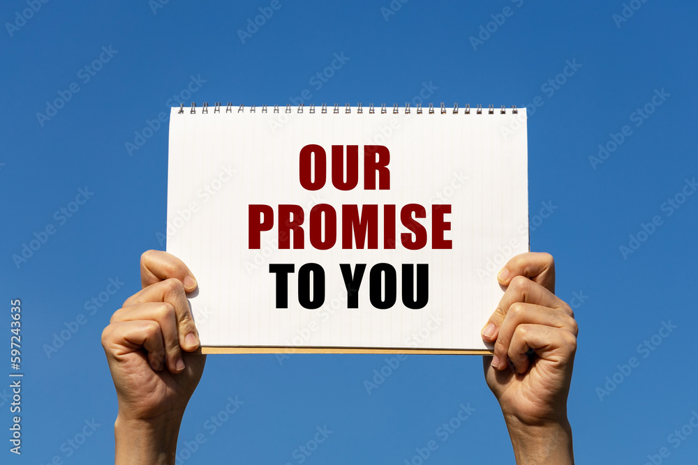 Poster our promise to you text on notebook paper held by 2 hands with isolated blue sky background. this me