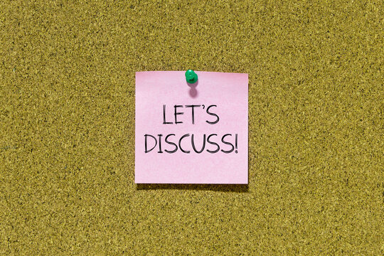 Let's discuss text on pink post-it paper pinned on bulletin cork board. This message can be used in business concept about let discuss.