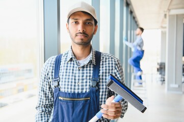 Young indian man washing window in office