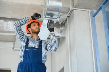 hvac indian worker install ducted pipe system for ventilation and air conditioning. copy space