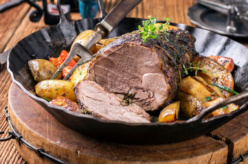 Traditional German barbecue lamb roast with vegetable  served as close-up in a rustic wrought iron...
