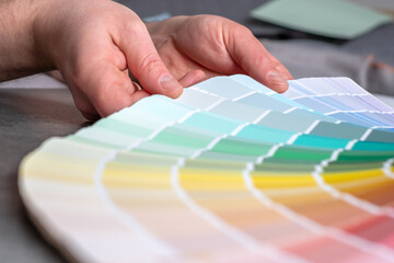 Hands designer or architect choosing swatch the colors painting of the wall in new apartment,...