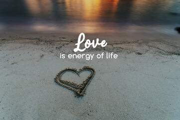 Heart shape on a sand beach with text Love is energy of life