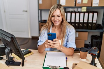 Young blonde woman ecommerce business worker using smartphone at office