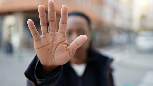 African american woman doing stop gesture with hand at street