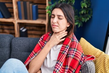 Young beautiful hispanic woman suffering for throat pain sitting on sofa at park