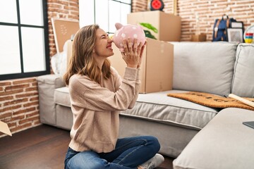 Young woman smiling confident holding piggy bank at new home