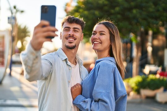 Young man and woman couple smiling confident making selfie by the smartphone at street