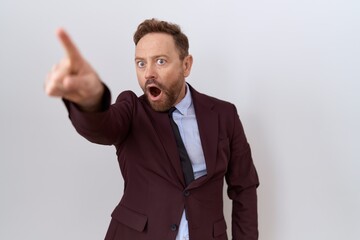 Middle age business man with beard wearing suit and tie pointing with finger surprised ahead, open mouth amazed expression, something on the front