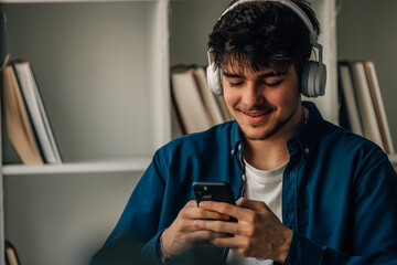 young man at home with mobile phone and headphones
