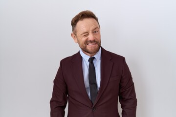 Middle age business man with beard wearing suit and tie winking looking at the camera with sexy expression, cheerful and happy face.