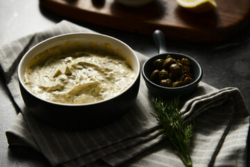 Classic Tartar Sauce with it ingredients on dark stone or marble background. Mayonnaise with dill and pickled cucumbers with lemon. 