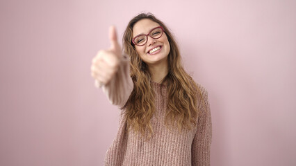 Young beautiful hispanic woman smiling confident doing ok sign with thumb up over isolated pink...