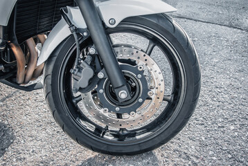 The front wheel of a racing motorcycle on the road.