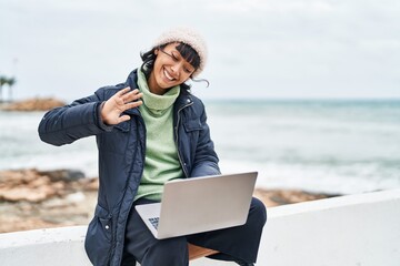 Fototapeta premium Young beautiful hispanic woman smiling confident having video call at seaside