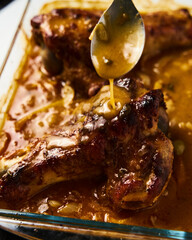 Smothered or stewed Turkey wings in a rectangular baking dish. Roasted to a crisp, the wings lie drowned in a thick gravy with vegetables. Food photo.