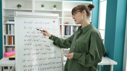 Young caucasian woman teaching maths on magnetic board at library university