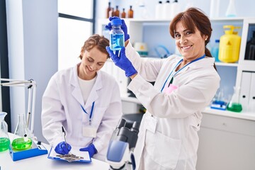 Two women scientists holding test tube writing on document at laboratory