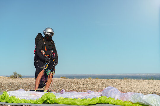 Man with professional flight suit and his paraglider ready for flying at the top of a hill on a sunny day